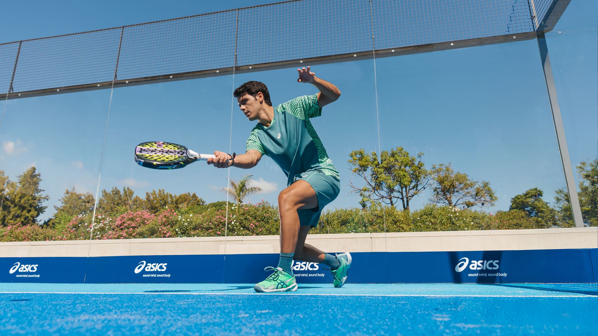 Padelio žaidėjas su ASICS padelio batais aikštelėje